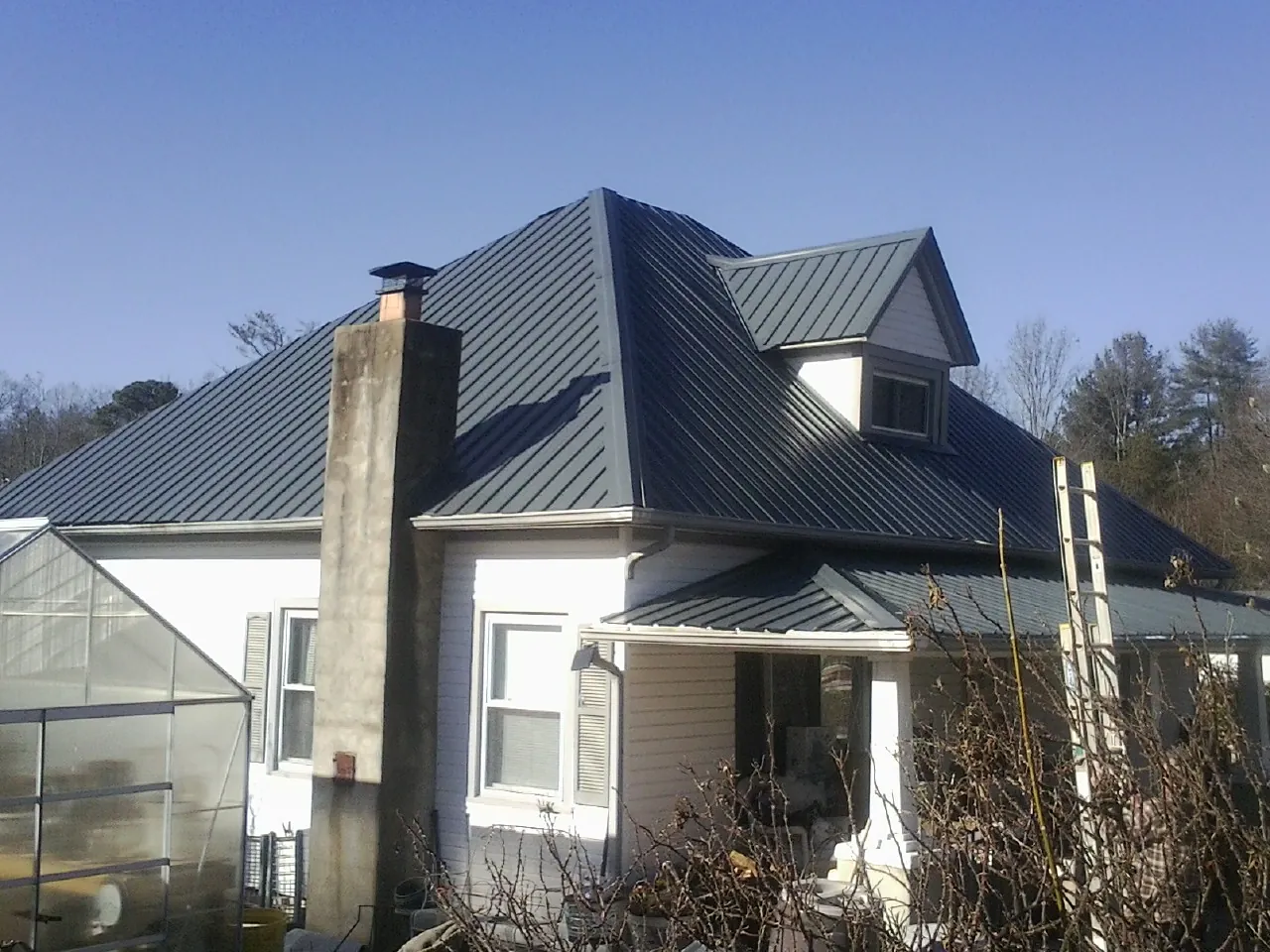 Dark blue standing seam metal roof on a white farmhouse with dormer — Slate & Tile Roof Repair by Roofing Brothers in Ecru