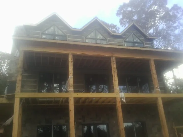 Dormers and porch framing on a large log home under construction — Roof Coating work by our crew in Ecru