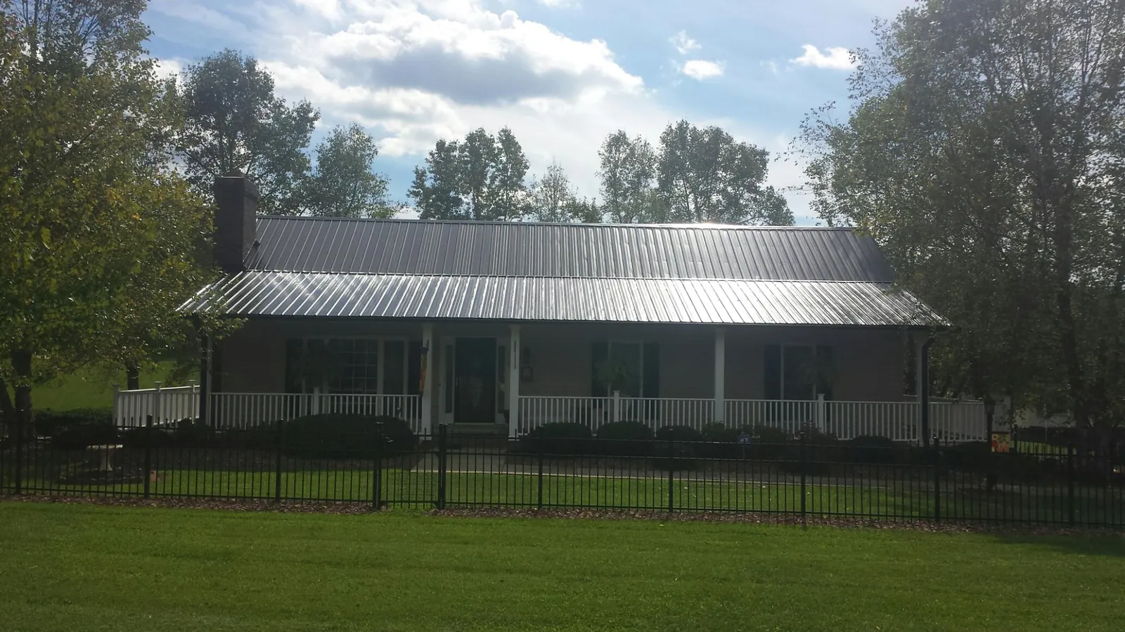 Gray metal roof on a brick ranch with a full width front porch — Gutter Guard Installation work by our crew in Ecru