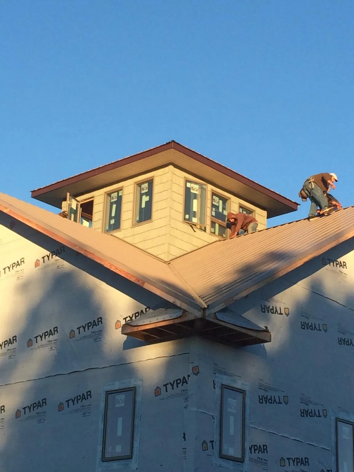 Roofers working around a rooftop cupola on a new metal roof at sunset — Roof Waterproofing in Ecru by Roofing Brothers